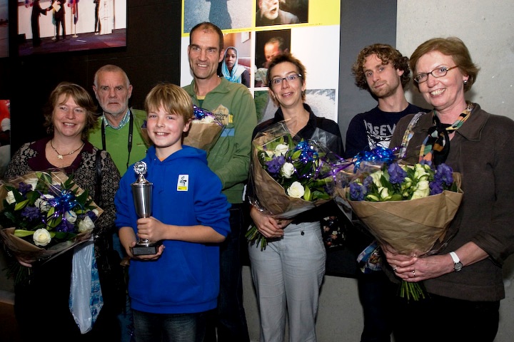 De prijswinnaars voor het bord met hun foto